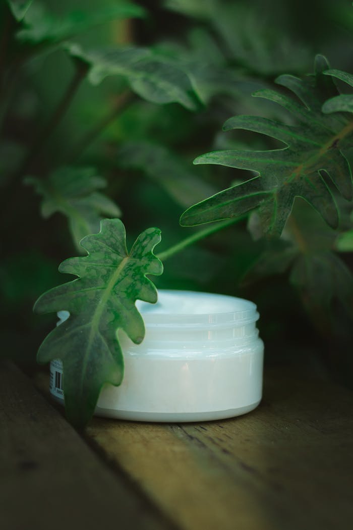 why-choose-us Close-up of skincare cream jar amidst lush green leaves, highlighting eco-friendly beauty.