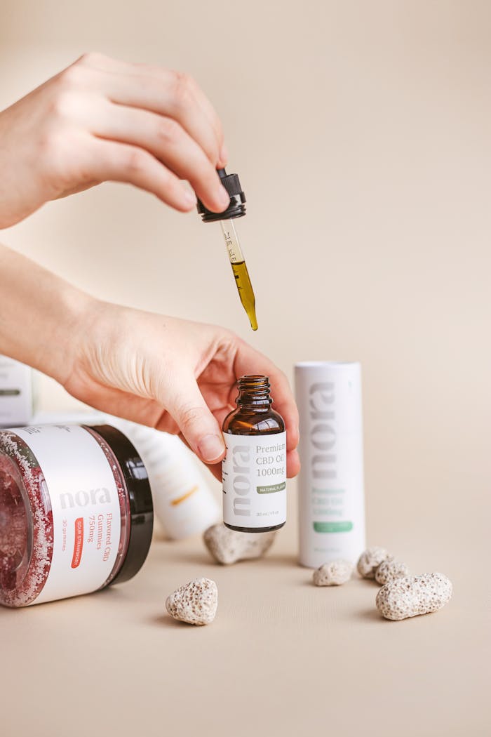 ours-journey Close-up of CBD oil dropper with products in a neutral studio setting, highlighting wellness theme.